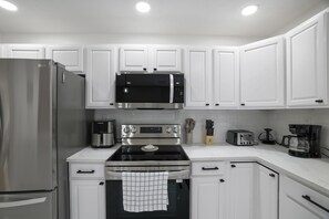 A modern kitchen with white cabinets, stainless steel appliances, and a clean layout. - Your Poconos Escape | Game Room • Firepit • Grill (Tobyhanna)