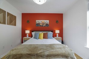 A bedroom with a bed, two bedside tables, a wall-mounted painting, and a window. - Your Poconos Escape | Game Room • Firepit • Grill (Tobyhanna)