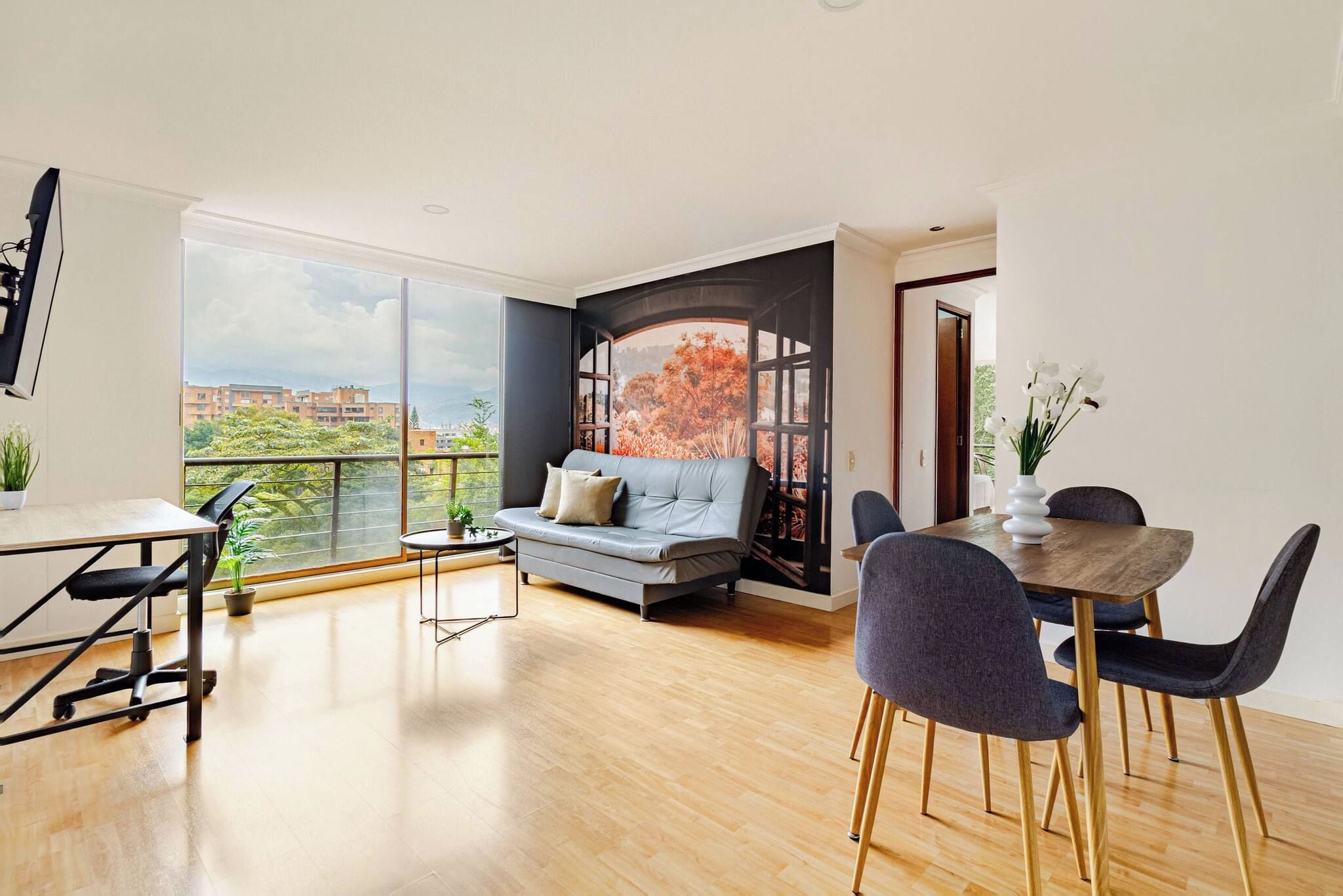 A modern living space with a dining area, a sofa, and a view of a cityscape.