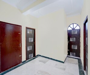 A hallway with two doors, one with a number plate, and a marble floor. - Classic Hotel Royal Brothers Stay (Danapur)