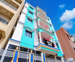 A multi-story hotel with balconies, a signboard, and a gated entrance.