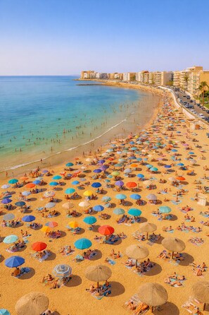Ein Strand mit vielen Sonnenschirmen und Menschen, die sich sonnen.
