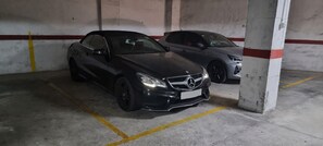 Eine Parkgarage mit zwei Autos, Betonpfeilern und gelben Markierungsstreifen.