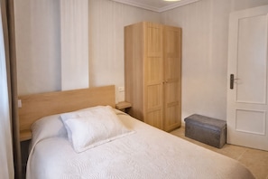 Ein Schlafzimmer mit Bett, Kleiderschrank, Nachttisch und einer Tür.