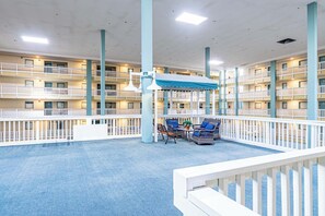 A spacious indoor atrium with a blue carpet, white railings, and wicker furniture under a blue canopy. - 2BR Resort Escape - Pools and Bars (Hilton Head Island)