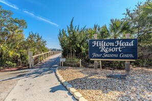 A pathway leading to Hilton Head Resort's Four Seasons Centre with a signboard. - 2BR Resort Escape - Pools and Bars (Hilton Head Island)