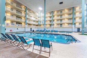 A multi-level hotel with a swimming pool, lounge chairs, and a lifeguard sign. - 2BR Resort Escape - Pools and Bars (Hilton Head Island)