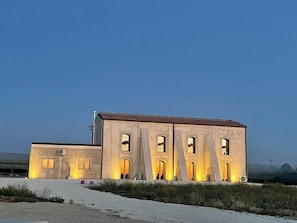 A building with multiple arched openings and a flat roof, situated in a desert-like environment with sparse vegetation. - B&B U'Minnulitu SALPIETRO (Caltagirone)