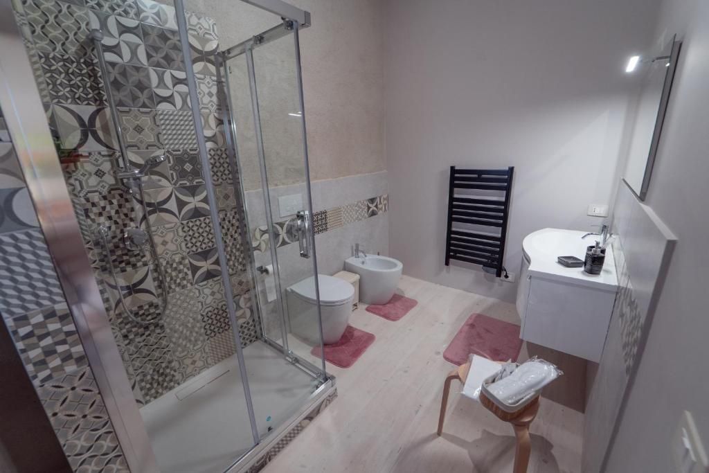 A bathroom with a glass shower enclosure, two sinks, and a toilet.