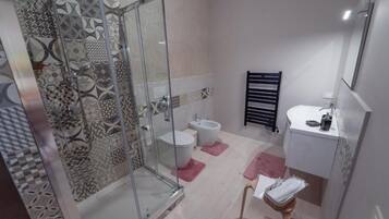 A bathroom with a glass shower enclosure, two sinks, and a toilet.