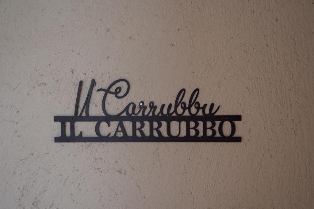 Eine Wand mit dem Text 'U' Carrubbu' und 'IL CARRUBBO' in einer verzierten Schriftart.