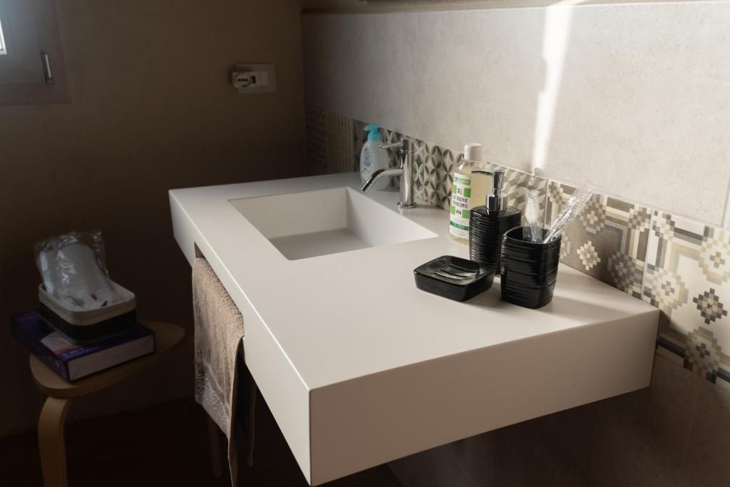 A bathroom with a white sink, a towel, a soap dispenser, and a toothbrush holder.