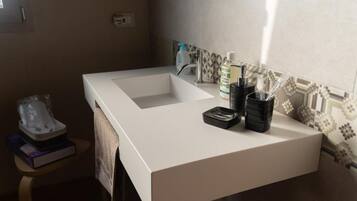 A bathroom with a white sink, a towel, a soap dispenser, and a toothbrush holder.