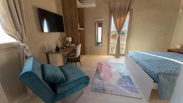 A bedroom with a bed, a desk, a chair, a sofa, and a TV.