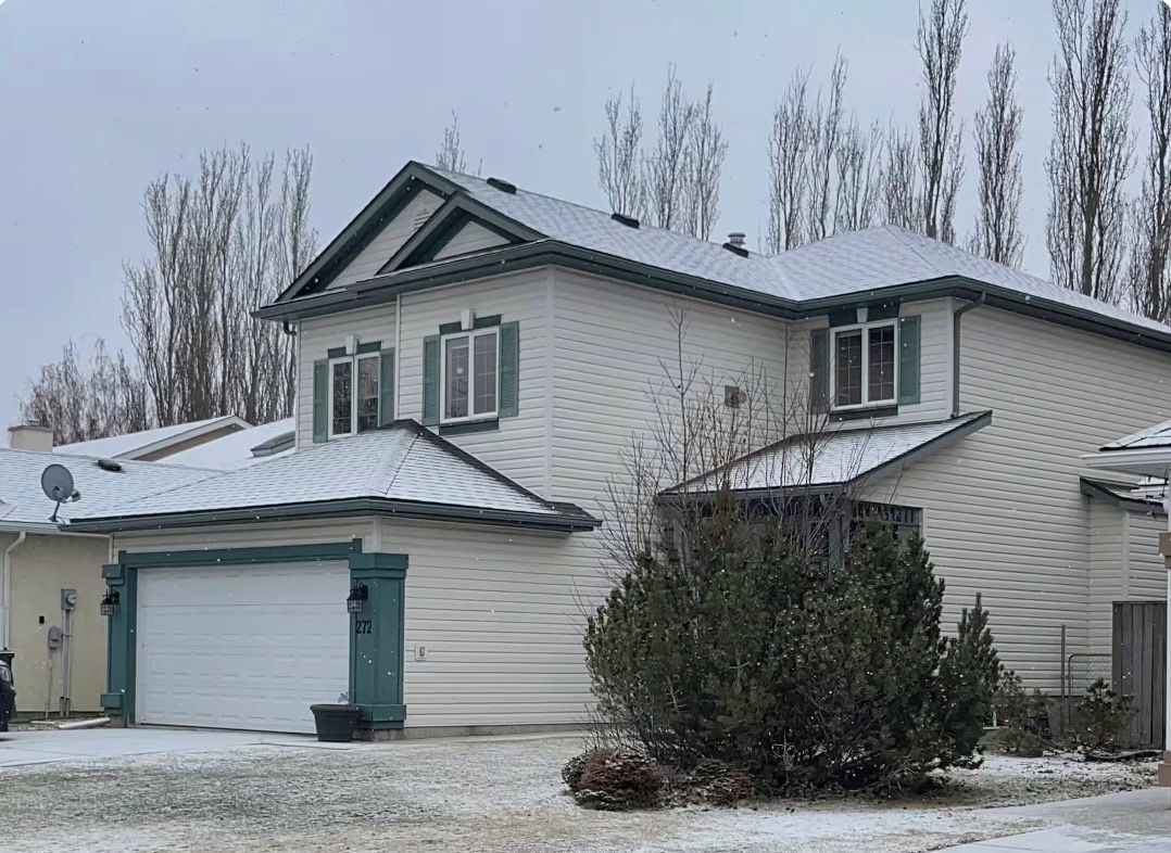 A two-story house with a garage, a satellite dish, and a snow-covered roof.