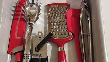 A drawer containing various kitchen utensils including a grater, a grater with holes, a grater with a red handle, a grater with a black handle, a grater with a red handle, a grater with a black handle, a grater with a red handle, a grater with a black handle, a grater with a red handle, a grater with a black handle, a grater with a red handle, a grater with a black handle, a grater with a red handle, a grater with a black handle, a grater with a red handle, a grater with a black handle, a grater with a red handle, a grater with a black handle, a grater with a red handle, a grater with a black handle, a grater with a red handle, a grater with a black handle, a grater with a red handle, a grater with a black handle, a grater with