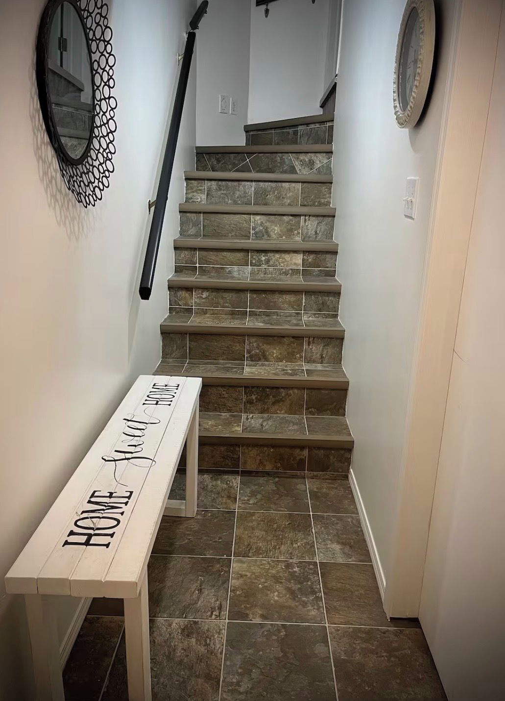 A staircase with a bench in the foreground and a wall-mounted mirror above it.