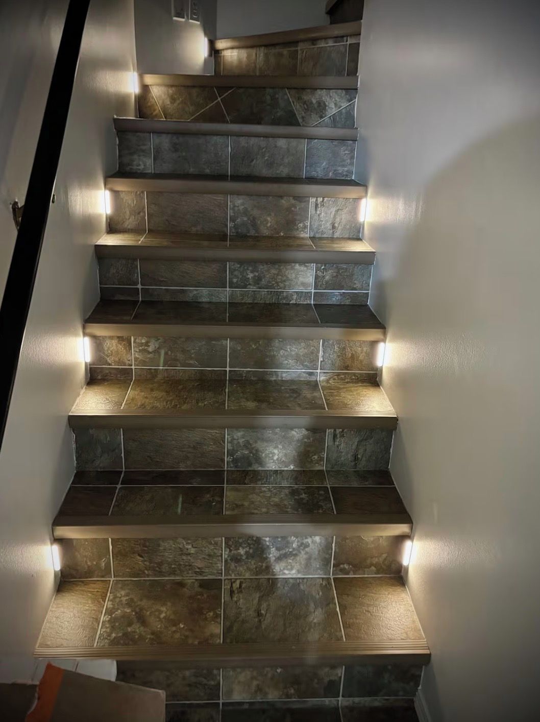 A staircase with a modern design, featuring a series of steps with a stone-like texture and integrated lighting along the edges.