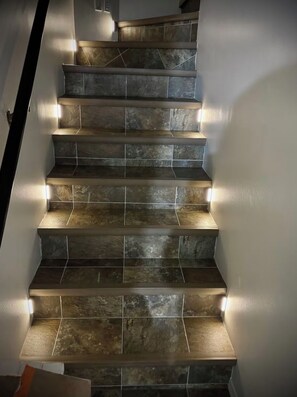 A staircase with a modern design, featuring a series of steps with a stone-like texture and integrated lighting along the edges.