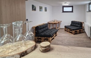 A room with a sofa and two chairs made from wooden pallets, a small round table, and a window with a view. - Stunning home in Sveti Martin na Muri with sauna (Sveti Martin na Muri)