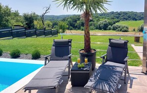 Zona piscina con due lettini e un tavolino con bevande e frutta.