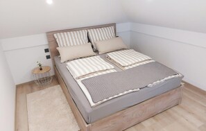 A bedroom with a bed, pillows, a bedside table, and a small plant. - Stunning home in Sveti Martin na Muri with sauna (Sveti Martin na Muri)