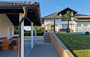 A covered outdoor area with a bench, a pathway leading to a house with a tiled roof, and a well-maintained lawn. - Stunning home in Sveti Martin na Muri with sauna (Sveti Martin na Muri)