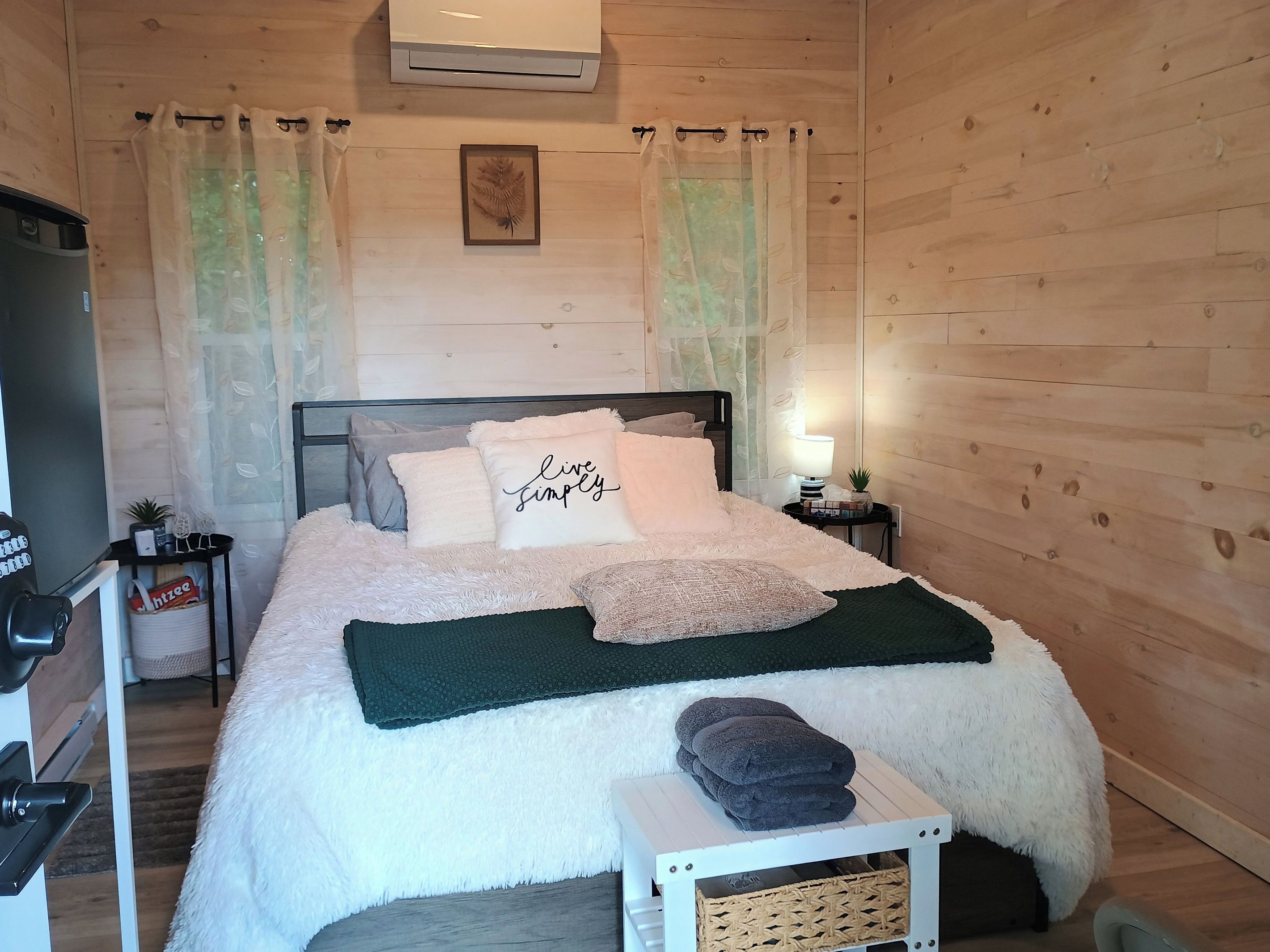 A bedroom with a bed, a bedside table, a lamp, and a small plant.