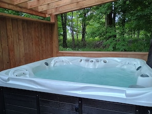 A hot tub with a wooden exterior and a view of a forested area.