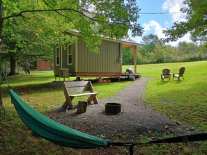 A rustic cabin with a porch, outdoor seating, and a hammock.