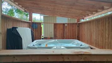A wooden hot tub with a cover, surrounded by wooden walls and a wooden ceiling.
