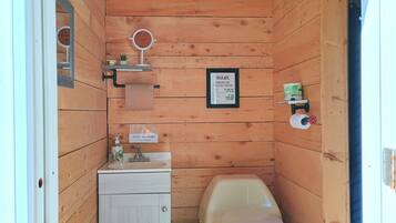 Une petite salle de bain en bois comprenant des toilettes, un lavabo et un miroir.