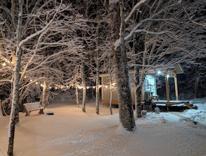 A snow-covered outdoor area with trees and a wooden structure, possibly a cabin or lodge.