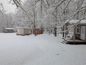 Un área al aire libre cubierta de nieve con varias cabañas de madera, cada una con un porche y una puerta.