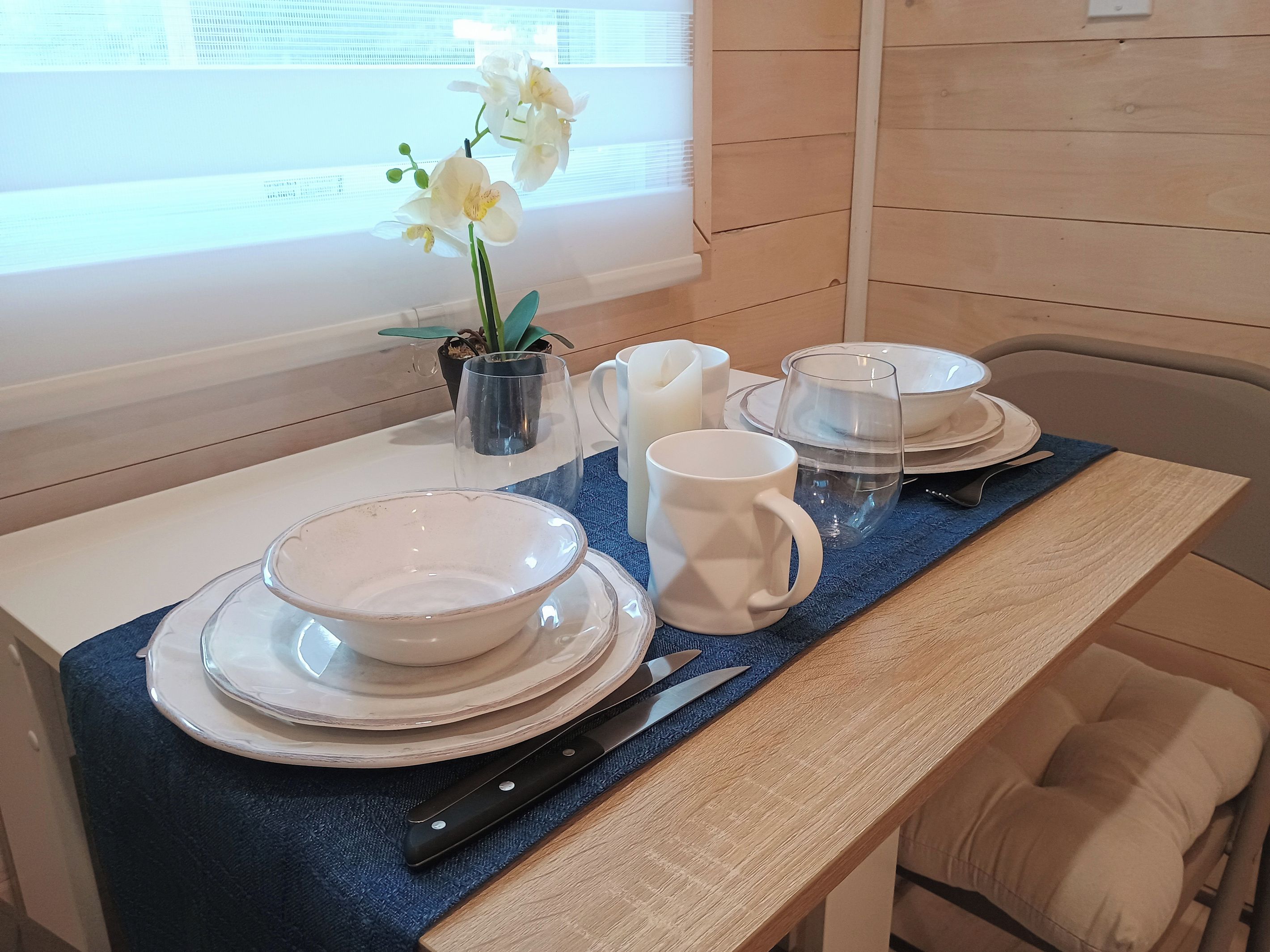A dining table set with white plates, bowls, a pitcher, and a mug.
