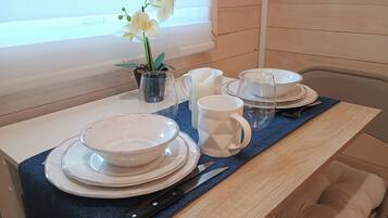 A dining table set with white plates, bowls, a pitcher, and a mug.