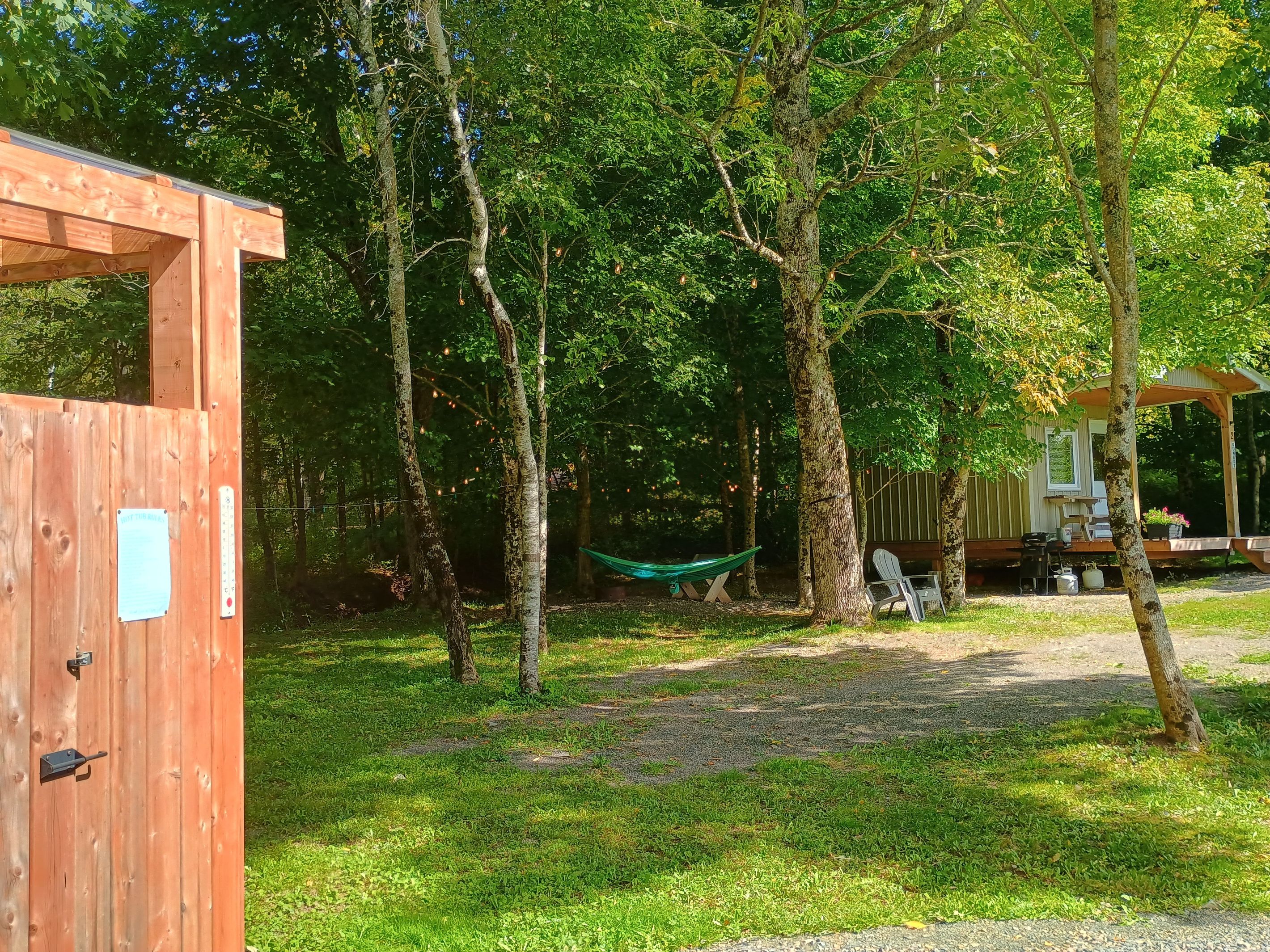 Eine Holzhütte mit Tür, umgeben von Bäumen und einer Hängematte.
