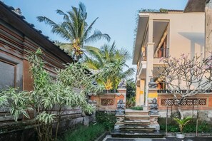 A traditional courtyard with a stone staircase leading to a building entrance, surrounded by tropical plants and a clear sky. - Quiet Balinese Stay in Ubud (Gianyar)