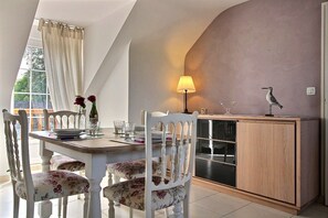 Uma sala de jantar com mesa, cadeiras, um armário e um abajur.