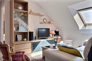 Ein modernes Wohnzimmer mit Fernseher, Bücherregalen, einer Couch und einem Oberlicht.