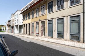 Une vue de rue d’une rangée d’immeubles avec de nombreuses fenêtres et portes, dont certaines sont dotées de volets.