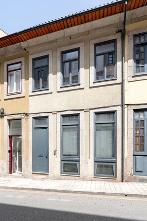 Ein Gebäude mit vielen Fenstern, einer roten Tür und einem Ziegeldach.