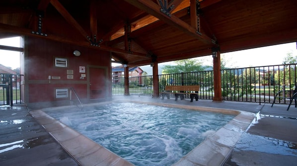 Un bain à remous situé sous un pavillon en bois, avec un banc et une clôture.