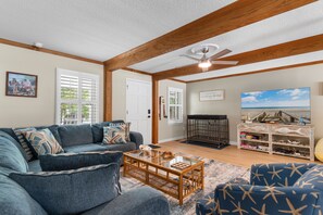 A living room with a sofa, a coffee table, a television, and a crib. - Hillside by the Sea - 5BR, sleeps 14, game room (North Myrtle Beach)