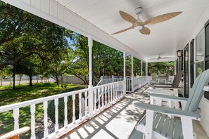 A covered porch with white railings, a ceiling fan, and outdoor furniture. - Hillside by the Sea - 5BR, sleeps 14, game room (North Myrtle Beach)