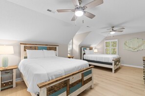 Ein Schlafzimmer mit zwei Betten, einem Deckenventilator und einem Fenster mit Jalousien.