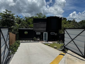 A modern two-story building with a concrete driveway leading to a gated entrance.