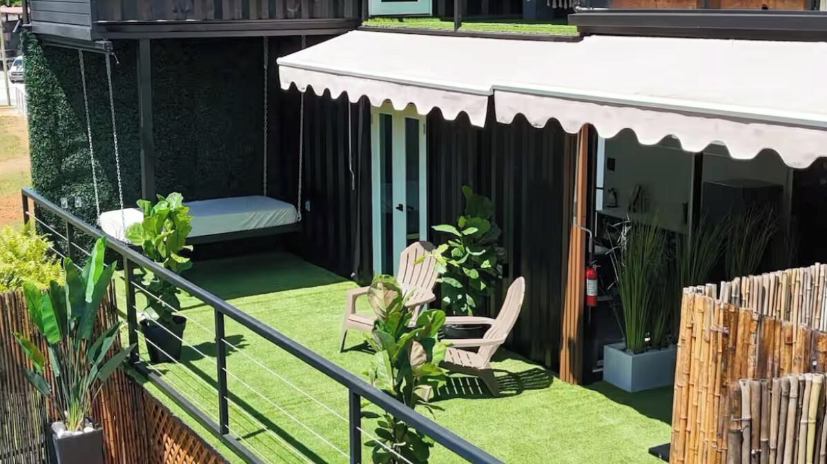 Eine Terrasse mit einer Schaukel, zwei Stühlen, einem kleinen Tisch und einem überdachten Sitzbereich.
