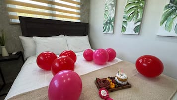 Ein Schlafzimmer mit einem Bett, Luftballons und einem Tablett mit Kuchen und Schleife.