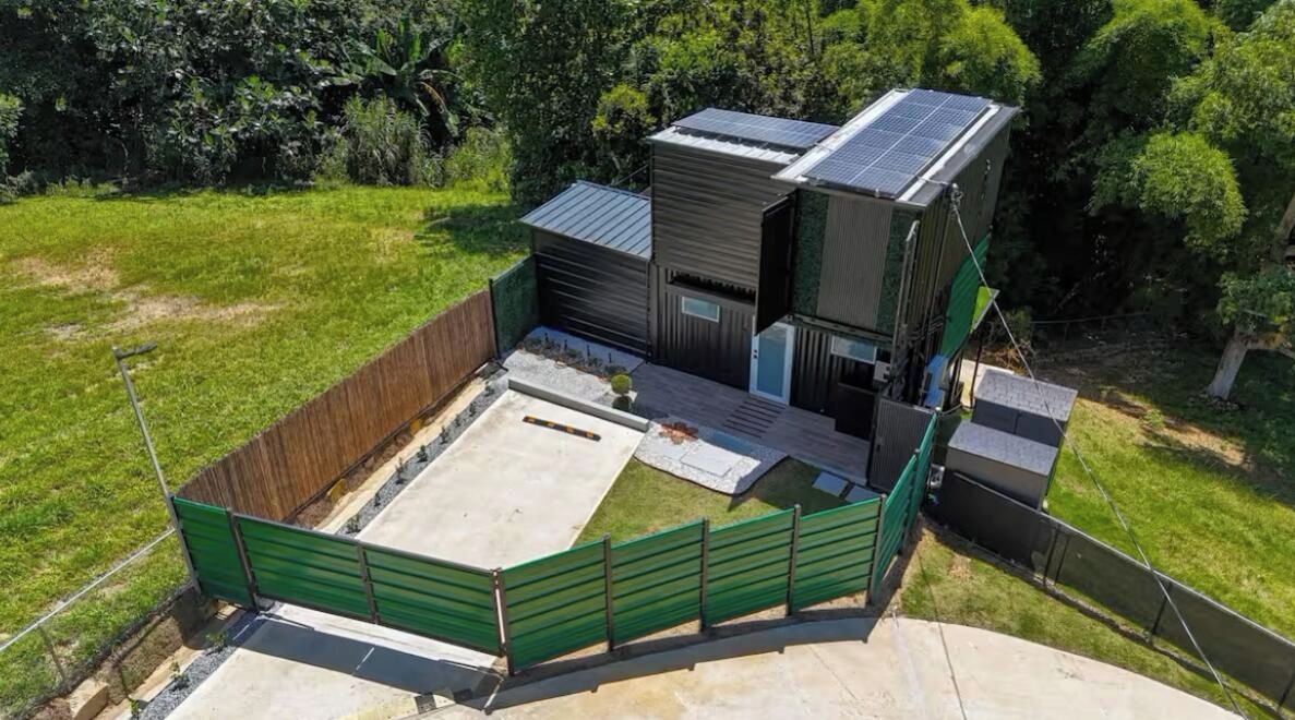 A modern building with solar panels, a fenced outdoor area, and a concrete patio.